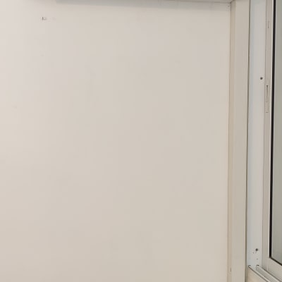 מזגן קיר לבן מותקן על קיר ליד חלון