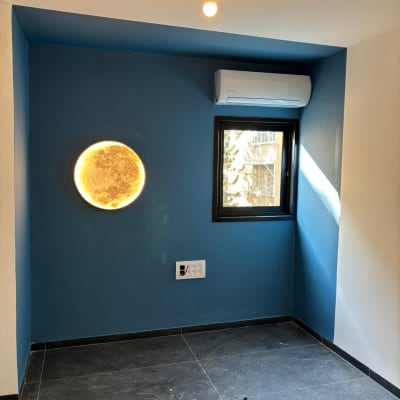 חדר צבוע בכחול עם מזגן ותאורה עגולה על הקיר