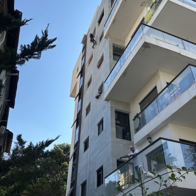 אדם עובד על בניין גבוה עם ציוד טיפוס