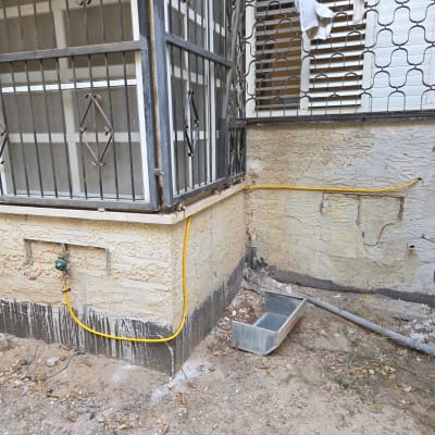 צינור גז צהוב מחובר לקיר חיצוני ליד חלון עם סורגים