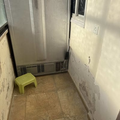 קיר עם קילופי צבע ושריטות, כיסא פלסטיק ירוק קטן