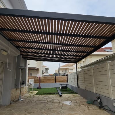 פרגולה מאלומיניום עם קורות עץ בחצר