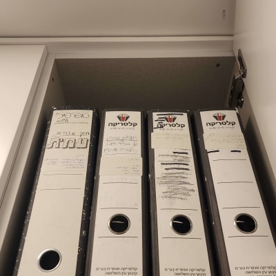 קלסרים מסודרים בארון לארגון מסמכים בבית.