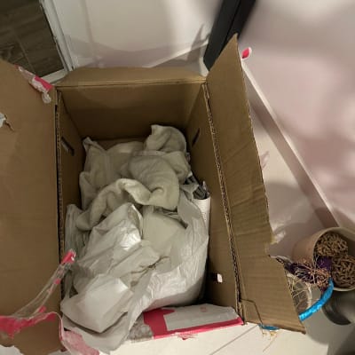 קופסה פתוחה עם בגדים וניירות על הרצפה