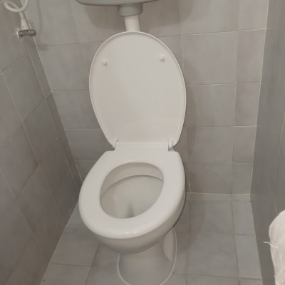 אסלה בחדר שירותים עם אריחי קרמיקה אפורים