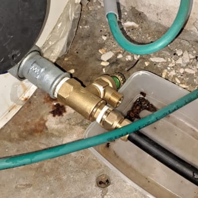 צינור ירוק מחובר לשסתום פליז על רצפת בטון