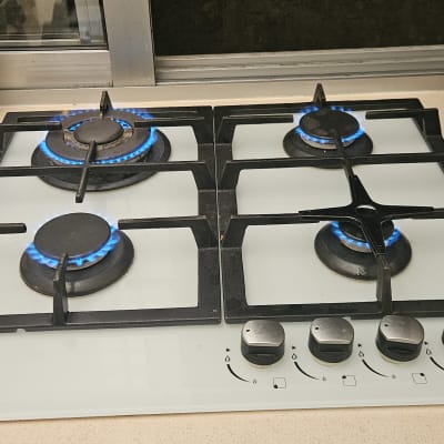 כיריים גז עם ארבעה מבערים דולקים ומצת על השיש