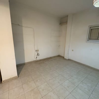 חדר ריק עם רצפת אריחים וקיר לבן