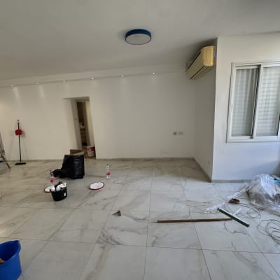 חדר עם כלים לצביעה, דלי ומברשות על הרצפה