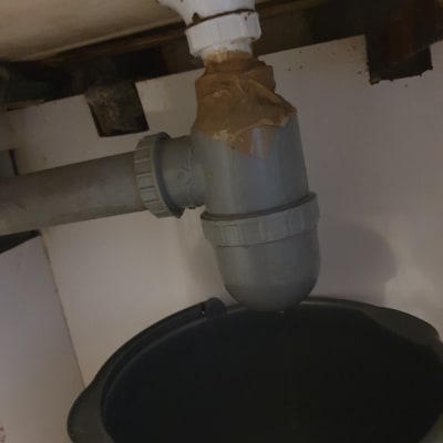 צנרת מתחת לכיור עם דליפה ודלי מתחת