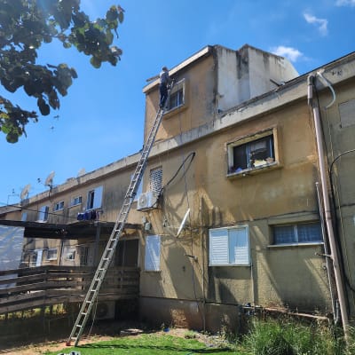 אדם על סולם מתקן גג של בניין