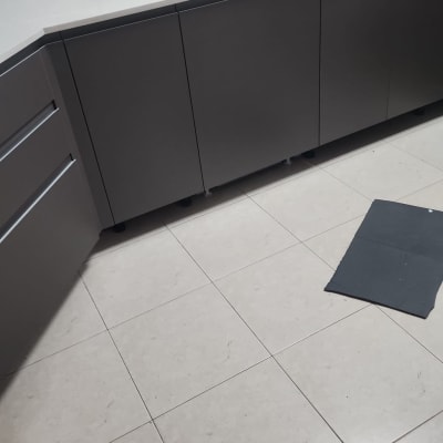 מטבח עם ארונות כהים, כיור וברז, חומרי ניקוי ומטליות