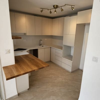 מטבח חדש עם ארונות לבנים ומשטח עץ