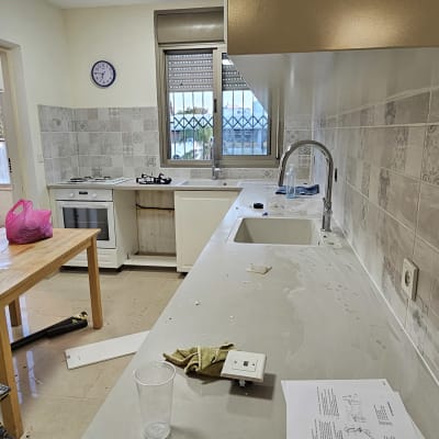 מטבח חדש עם ארונות לבנים ומשטח עבודה