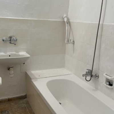 אמבטיה עם אריחים לבנים וברז מקלחת