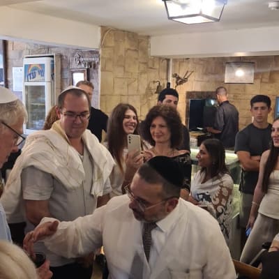 איש בחלוק לבן עם כיפה, מוקף אנשים