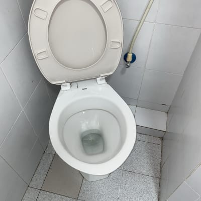 אסלה פתוחה עם צינור מים מחובר לקיר