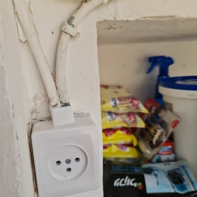 שקע חשמל עם חוטים חשופים על קיר לבן