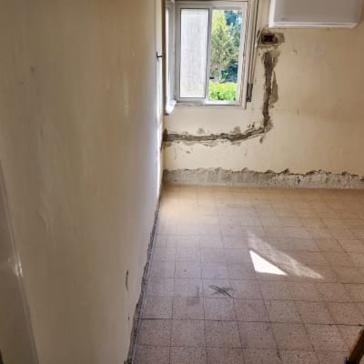 קיר עם טיח מתקלף וחלון פתוח בחדר בשיפוץ