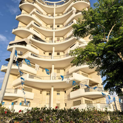 בניין מגורים עם מרפסות ודגלים כחולים ולבנים