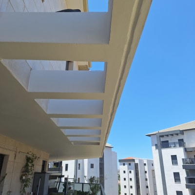 מרפסת עם צמחייה ומבנים ברקע בשמיים כחולים