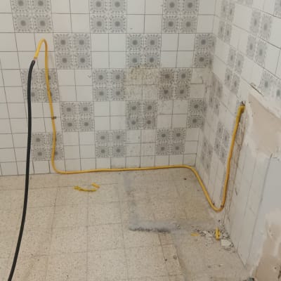 חדר עם אריחים לבנים וצינור גז צהוב