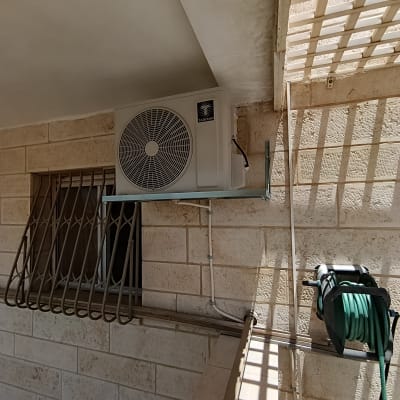 יחידת מזגן מותקנת על קיר חיצוני עם צינור ירוק