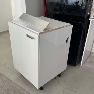 ארון לבן עם ידית מתכת על רצפה אפורה