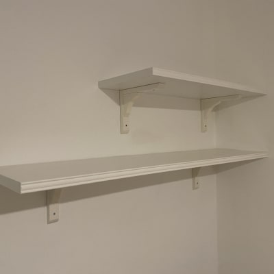 שתי מדפים לבנים מותקנים על קיר עם תומכים