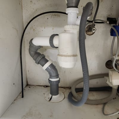 צנרת פלסטיק מתחת לכיור עם מחברים אפורים