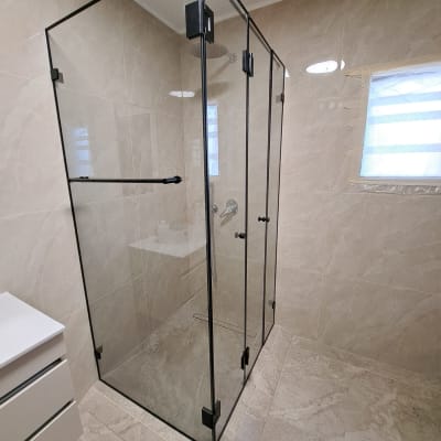 מקלחון זכוכית בחדר אמבטיה מודרני עם אריחים בהירים