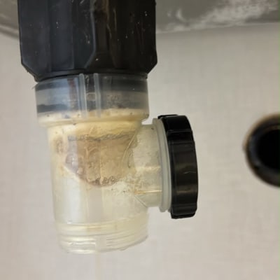 סתימת שומן בסיפון הניקוז מתחת לכיור במהלך טיפול אינסטלציה