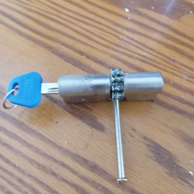 מנעול גלילי עם מפתח וברגים על שולחן עץ.