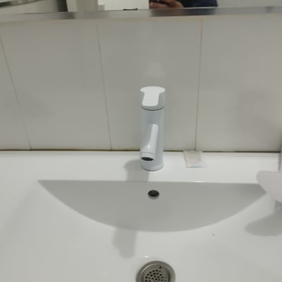 ברז לבן על כיור לבן עם ניקוז מתכת