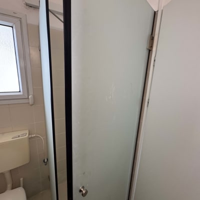 דלת מקלחת מזכוכית בחדר אמבטיה עם חלון ושירותים