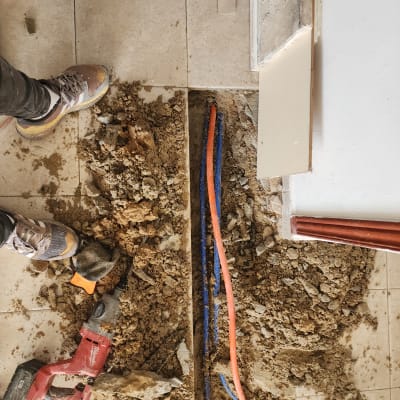 תיקון צנרת מתחת לרצפה עם כלי עבודה ואדמה חשופה