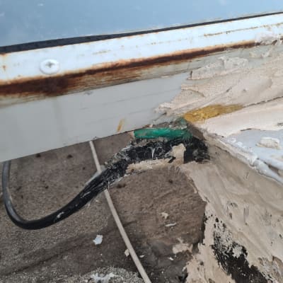 חוט חשמל שחור מחובר למשטח מתכת חלוד