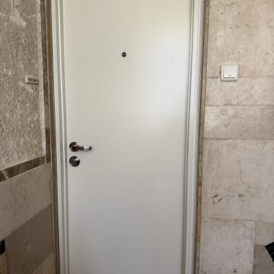 דלת לבנה עם ידית מתכת בקיר אבן