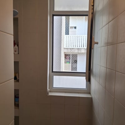 חלון אלומיניום פתוח בחדר אמבטיה עם אריחים לבנים