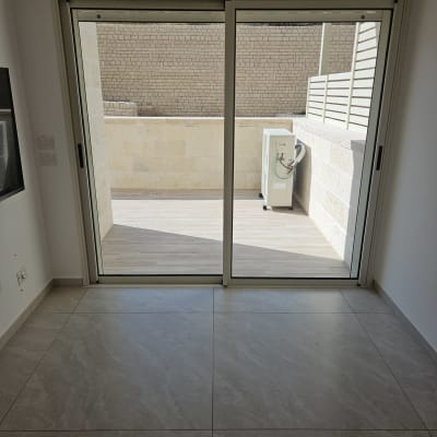 חדר עם רצפת אריחים ודלת זכוכית למרפסת