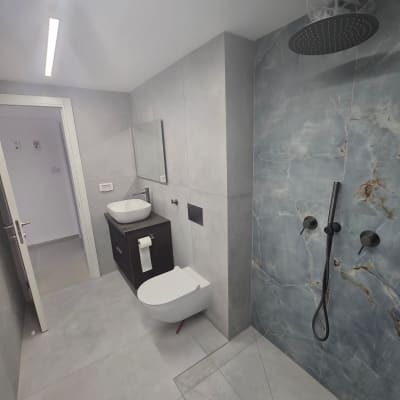 חדר אמבטיה עם מקלחון, כיור ואסלה תלויה