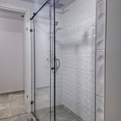 מקלחת עם דלת זכוכית וראש מקלחת