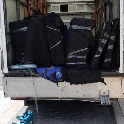 משאית פתוחה עם רהיטים עטופים בשמיכות שחורות