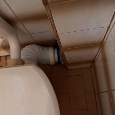 אסלה עם צינור חיבור לבן בפינה