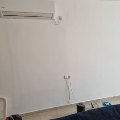 קיר צבוע עם מזגן וחפצים על הרצפה