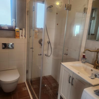 מקלחון זכוכית עם כיור וברז זהב בחדר אמבטיה