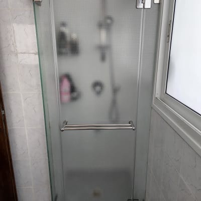 דלת זכוכית למקלחת עם בקבוקי שמפו