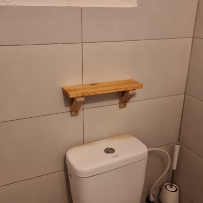 מדף עץ מותקן מעל אסלה בחדר אמבטיה
