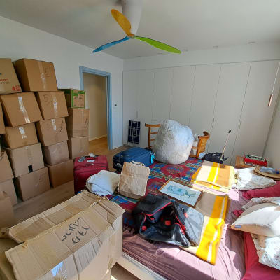 חדר עם קופסאות קרטון, מיטה ומזוודות