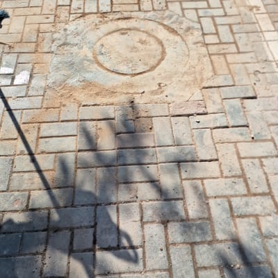 מכסה ביוב עגול על מדרכה מרוצפת